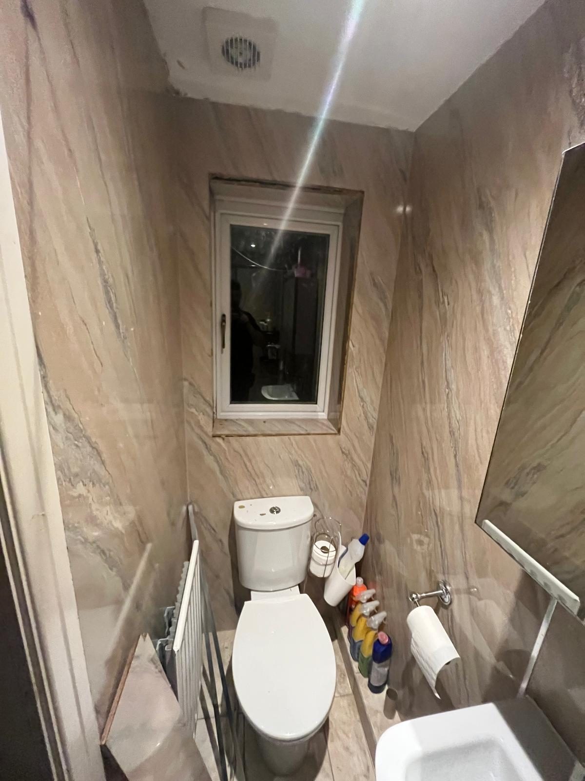Narrow WC with beige wall panels and radiator before a bathroom refit