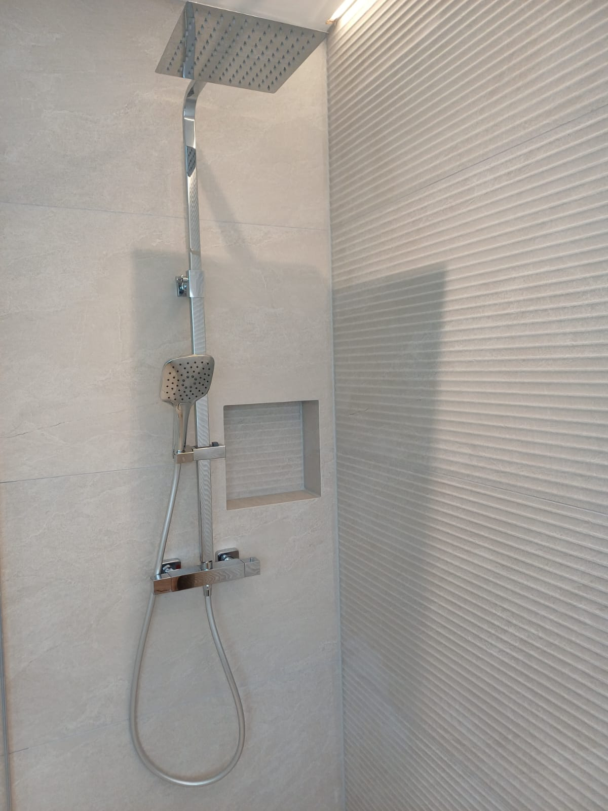 Chrome rainfall shower riser with thermostatic valve and recessed shelf niche fitted in a new shower