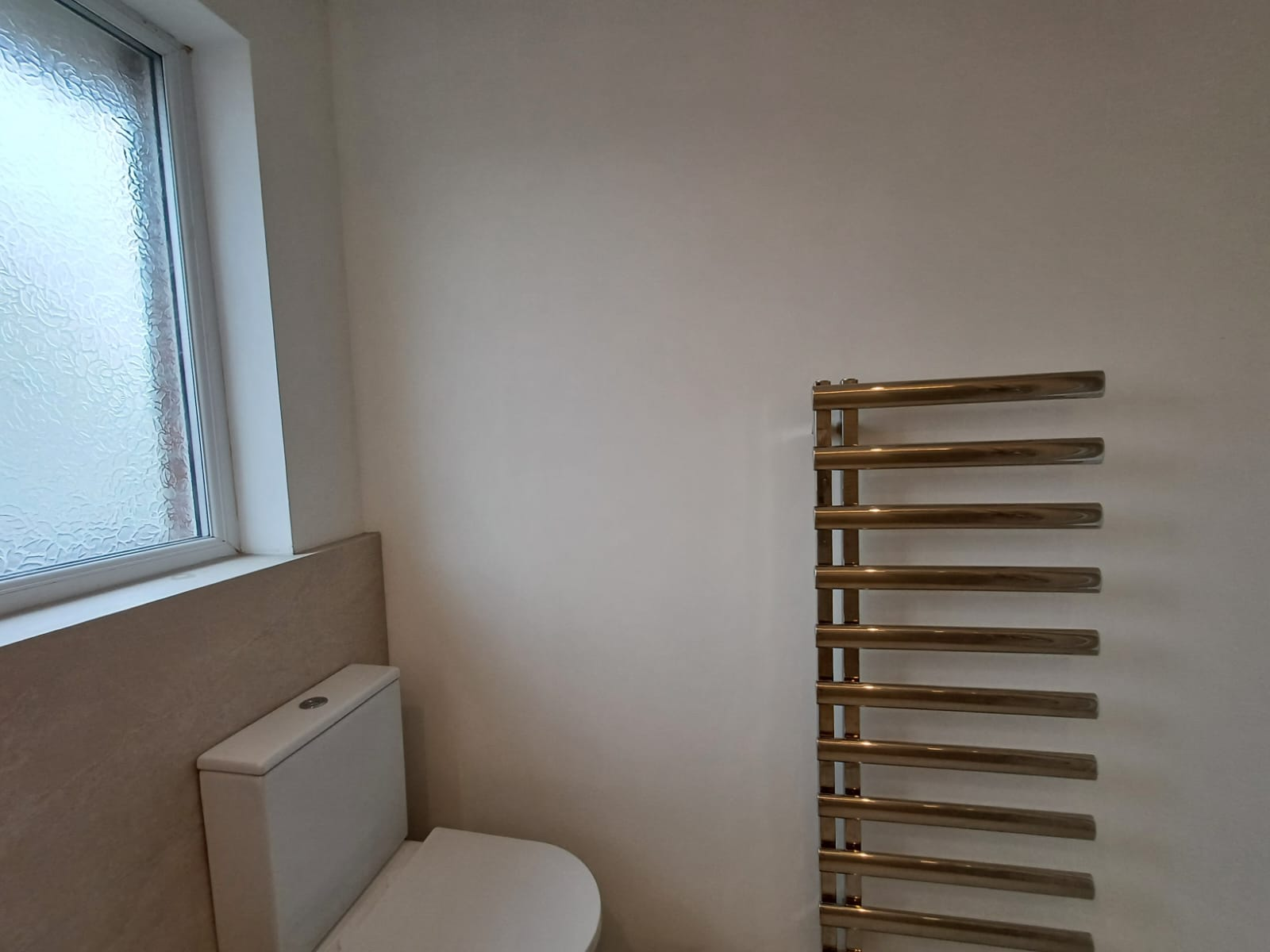 Finished WC with concealed cistern toilet and brushed gold heated towel rail